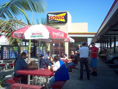 1988 Ford Bronco - People gather at a Sonic Drive-In on a sunny day, with cars visible in the background.