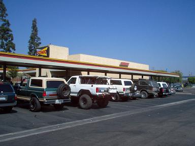 1988 Ford Bronco - Several SUVs and trucks are parked in a lot outside a Sonic restaurant.