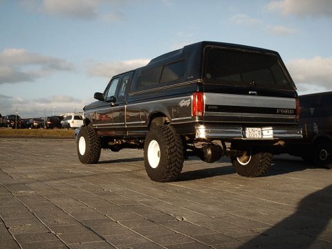 1996 Ford Bronco - This Ford pickup truck has a camper shell and is lifted with large tires. The license plate is visible.