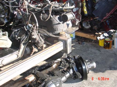 1991 Ford F-150 - A collection of vehicle parts, including engine components and a chassis, are scattered on a concrete surface.
