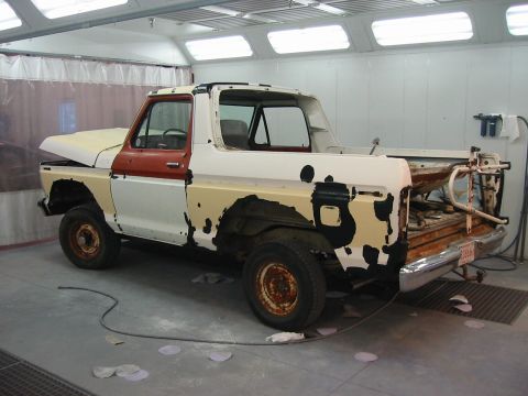 1992 Ford Bronco - This Ford Bronco appears to be undergoing restoration work in a paint booth, with primer visible beneath peeling paint.