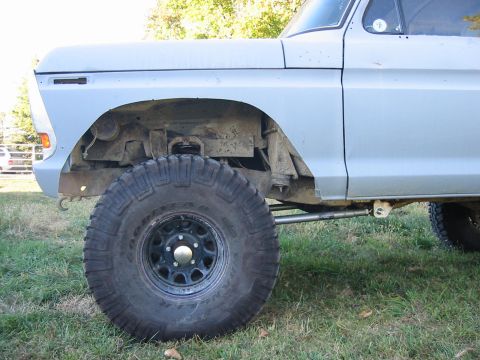 1992 Ford Bronco - Side view of a light blue pickup truck's front fender and large tire, showing lifted suspension components.