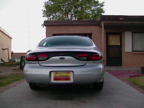 1999 Ford Taurus - Rear view of a silver 1999 Ford Taurus parked in a driveway in front of a house.