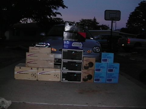 1999 Ford Taurus - A collection of car stereo equipment is displayed in front of a 1999 Ford Taurus.