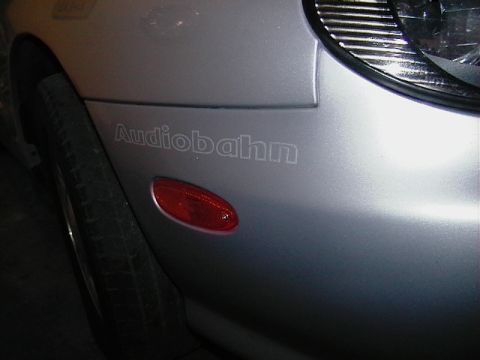 1999 Ford Taurus - Close-up of a car's fender showing a red side marker and an 'Audiobahn' decal.