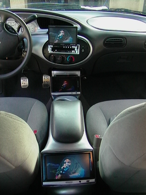 1999 Ford Taurus - The interior of a 1999 Ford Taurus features multiple aftermarket screens installed in the dashboard and center console.