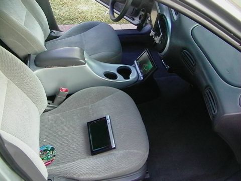 1999 Ford Taurus - The interior of a car shows gray cloth seats and a center console with a mounted tablet display.