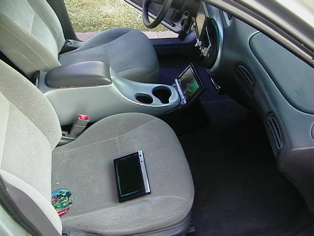 Car interior with gray cloth seats, center console with cup holders, and a tablet mounted on the dashboard