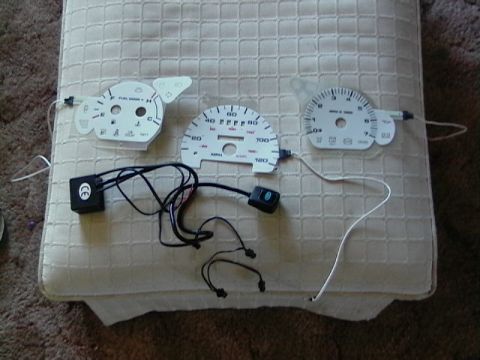 1999 Ford Taurus - These are replacement gauge faces for a vehicle's instrument cluster, laid out on a padded surface.