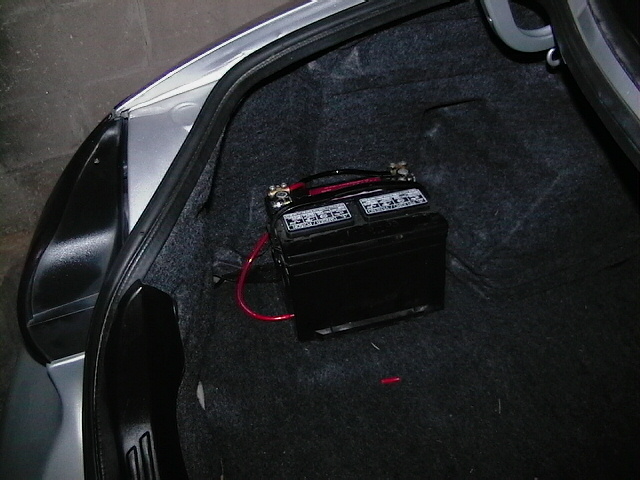 Car battery with red cables in a car's trunk