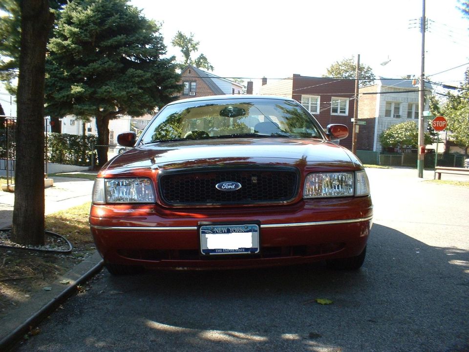Front of a maroon Ford Crown Victoria parked on a residential street
