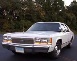 1991 Ford LTD Crown Victoria - This white Ford sedan is parked outdoors with trees in the background. The grille and body style suggest an earlier model year.