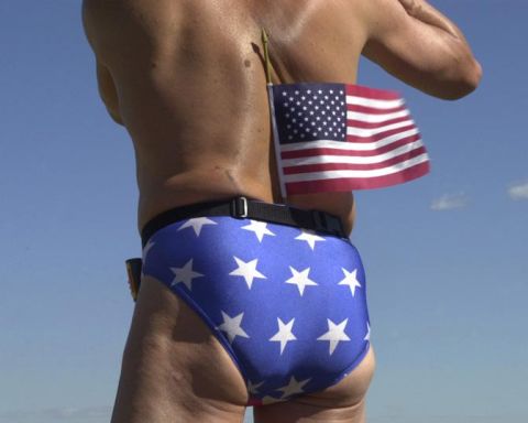 1988 Ford Bronco - A man stands outdoors, his back to the camera, wearing star-spangled briefs and holding an American flag.