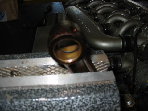 1993 Ford Taurus - Close-up of an engine connecting rod bearing held in a vise, with part of the intake manifold visible behind it.
