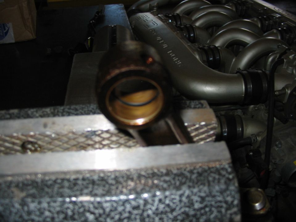 Connecting rod small end with new bronze wrist pin bushing, tubular intake manifold behind