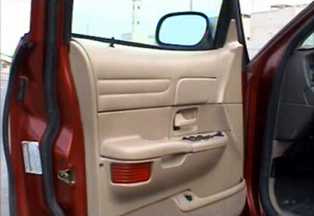 2000 Ford Crown Victoria - Interior view of a red 2000 Ford Crown Victoria showing the driver's side door panel and controls.