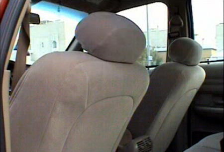 2000 Ford Crown Victoria - The interior of the vehicle shows beige cloth seats and headrests, with a view of buildings through the windows.