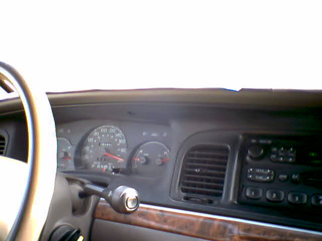 Dashboard of a 2000 Ford Crown Victoria with wood trim and a column shifter