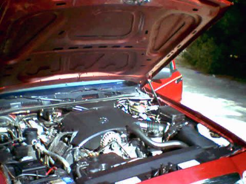 2000 Ford Crown Victoria - Engine bay of a red car. The hood is open, revealing the engine and surrounding components.