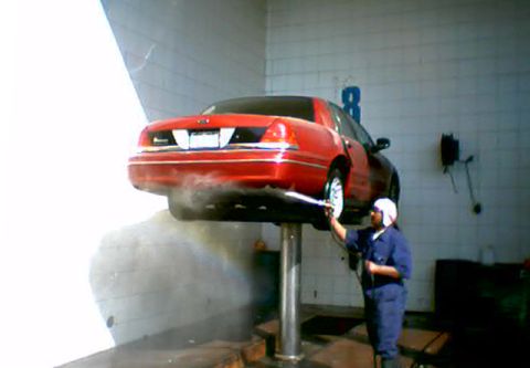 2000 Ford Crown Victoria - A mechanic washes the rear of a red 2000 Ford Crown Victoria on a car lift.