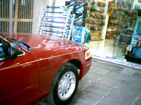 2000 Ford Crown Victoria - A red sedan is parked indoors, with a metal shelving unit visible behind it.