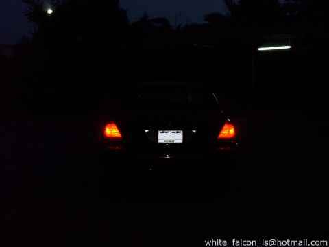 2000 Ford Crown Victoria - A dark sedan is parked at night, its taillights illuminated.