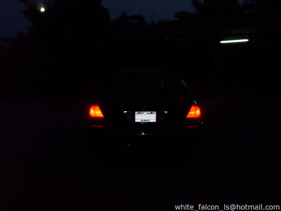 Rear of a dark sedan with taillights on, license plate visible