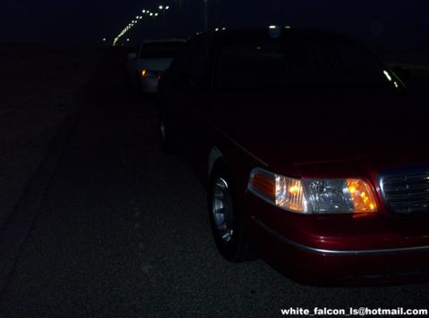 2000 Ford Crown Victoria - Front corner of a 2000 Ford Crown Victoria is visible at night, with another vehicle behind it.