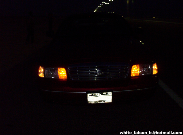 front of red sedan with Kuwait license plate at night
