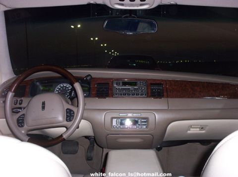 2000 Ford Crown Victoria - The interior of a car is shown at night, wood grain accents on the dashboard and center console.