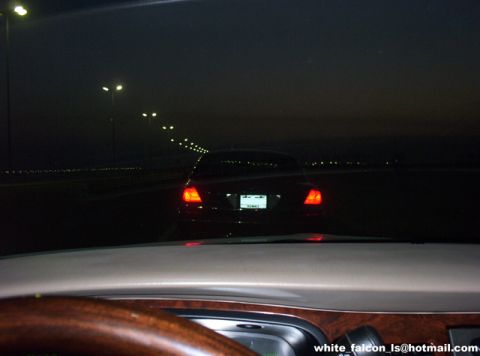 2000 Ford Crown Victoria - A car's taillights glow in the darkness as it drives down a highway at night.