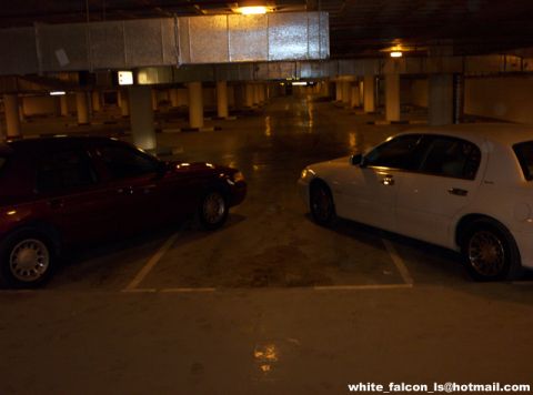 2000 Ford Crown Victoria - Two sedans, a maroon 2000 Ford Crown Victoria and a white vehicle, are parked in a parking garage.