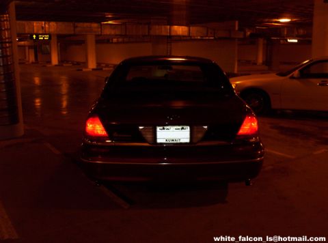 2000 Ford Crown Victoria - A dark sedan is parked in a dimly lit garage, its taillights glowing, with another vehicle visible in the background.