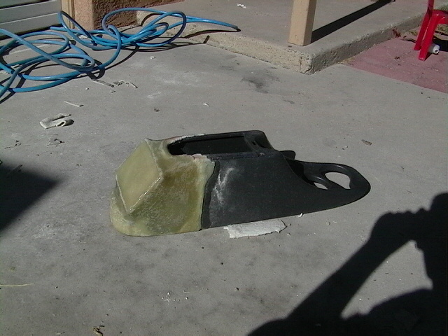 Custom car dashboard part made of fiberglass and black plastic, sitting on concrete