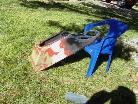 1999 Ford Taurus - A weathered car dashboard section rests on a blue chair on a grassy lawn.