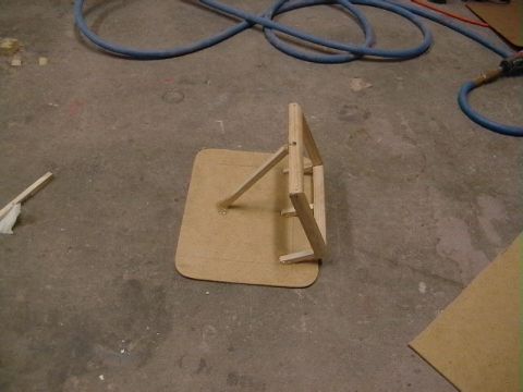 1999 Ford Taurus - A wooden jig is shown on a concrete floor, with blue hoses visible in the background.