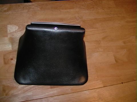 1999 Ford Taurus - This is a black plastic car part with a silver trim piece and a small circular fastener.