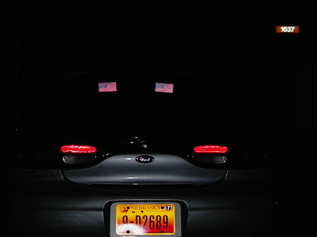 Rear of a 1999 Ford Taurus with Nebraska plates and two small American flags on the back window