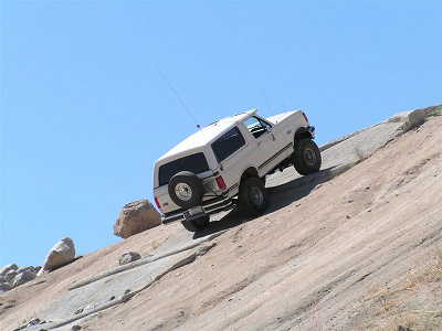 1988 Ford Bronco - A white 1988 Ford Bronco navigates a challenging rocky terrain, its off-road capabilities.