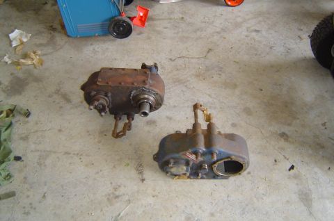 1993 Ford Bronco - Two old transfer cases are shown on a concrete floor, with a blue cart and tire in the background.
