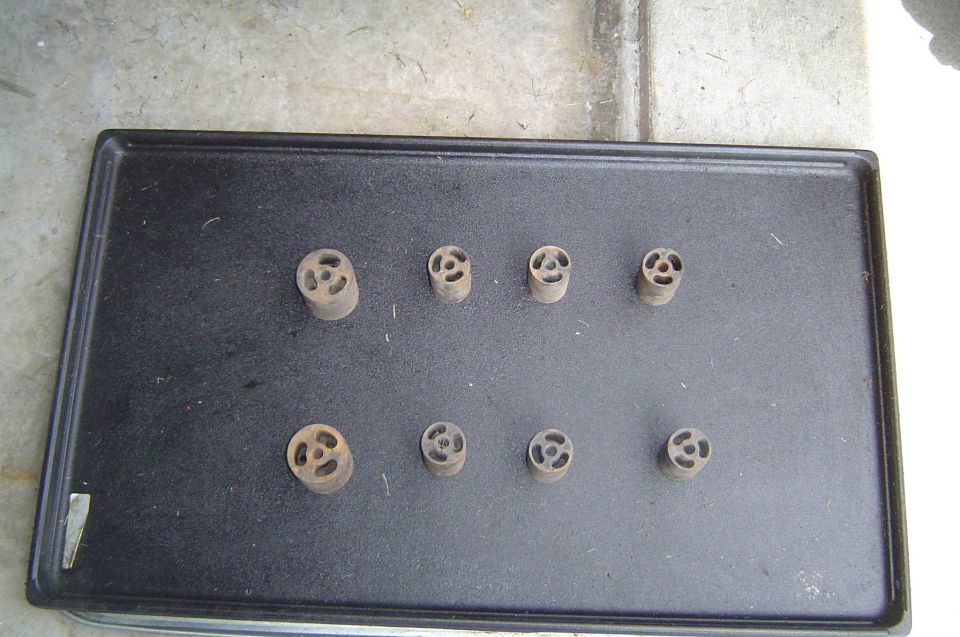 Eight cylindrical body lift spacer pucks arranged on a black tray on concrete