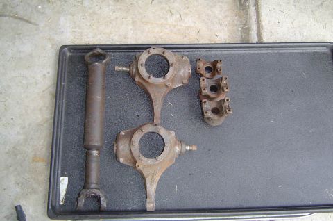 1993 Ford Bronco - Several rusty automotive drivetrain components are laid out on a black tray.