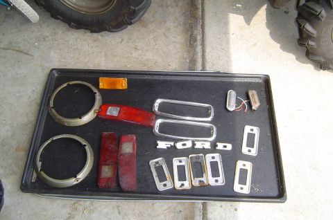1993 Ford Bronco - Various Ford Bronco parts are laid out on a tray, including taillights and emblems.