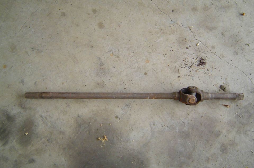 Rusty front axle shaft with U-joint laid on concrete floor