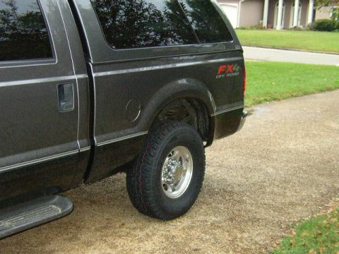 1995 Ford Bronco - Rear side view of a dark gray pickup truck with a camper shell and FX4 Off Road decal.