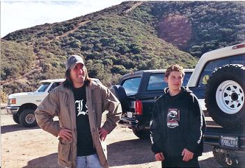 1988 Ford Bronco - Two men stand next to a white 1988 Ford Bronco and a black SUV in a hilly, outdoor landscape.