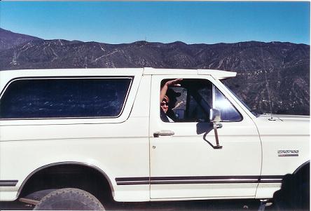 1988 Ford Bronco - 1988 Ford Bronco parked with mountains behind it. Person waves from the driver's side window.
