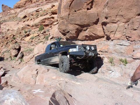 1993 Ford Bronco - A black pickup truck tackles a challenging off-road course amidst towering red rock formations.