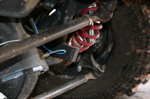 1993 Ford Bronco - Close-up view of off-road vehicle suspension system with red coilover shock absorber and knobby tire.