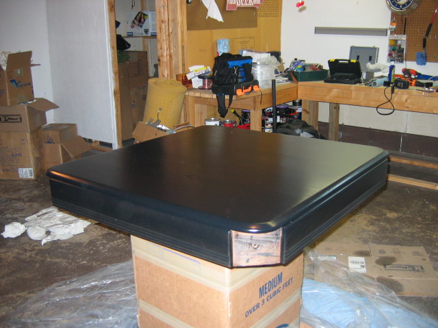 Black table on top of cardboard boxes in a cluttered garage